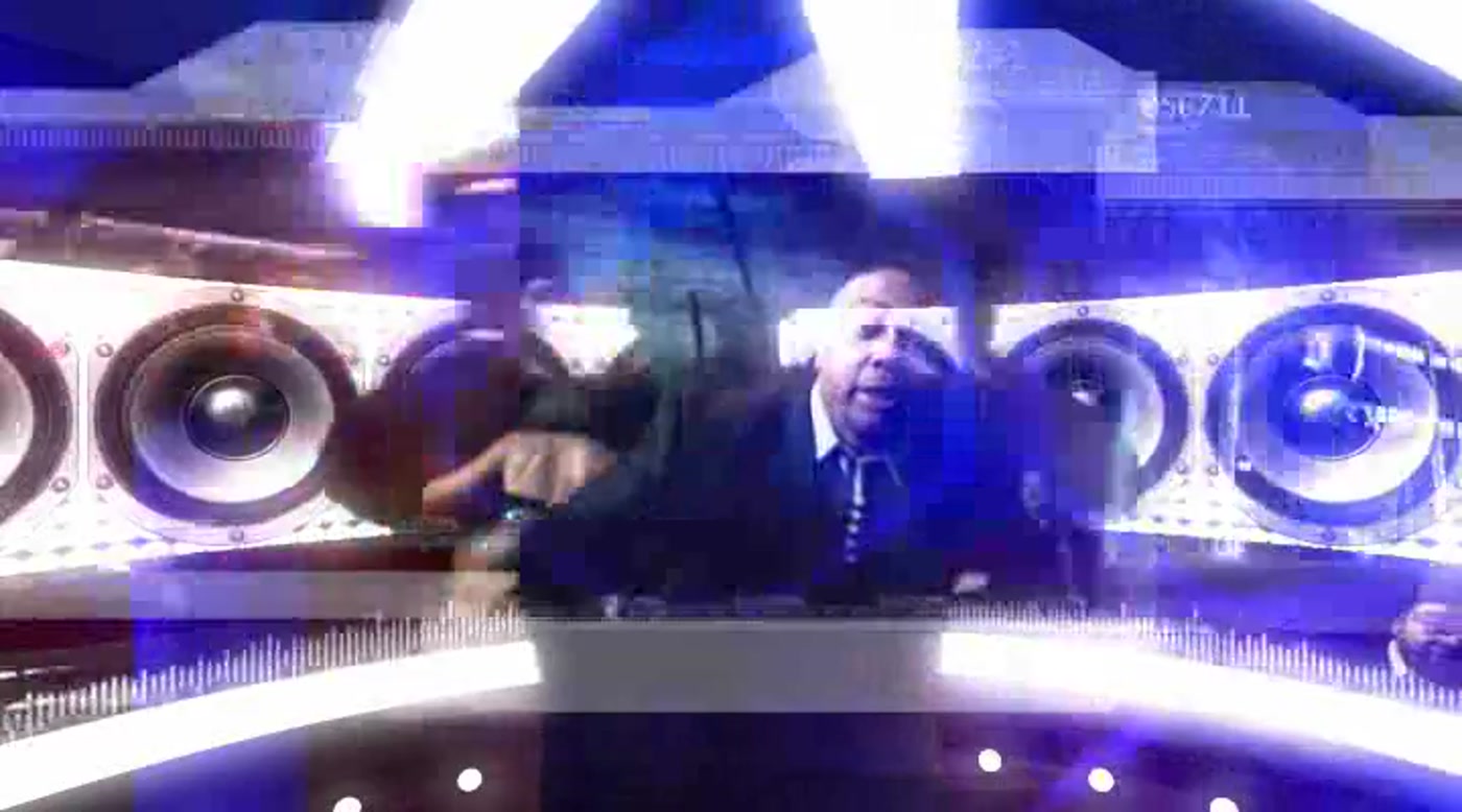 Frame from a broadcast set with a wall of studio monitors